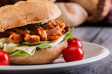 Fried chicken meat with cheese and vegetables in bun