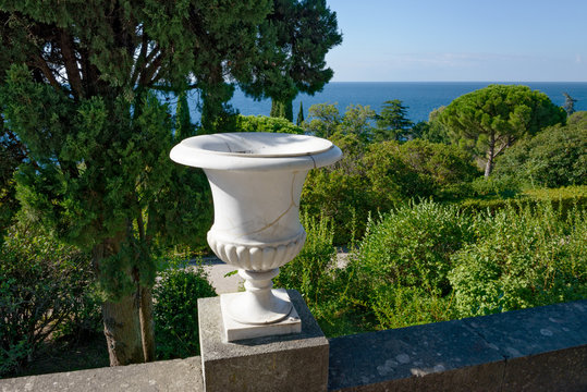 Classical marble vase on parapet in garden by the sea.