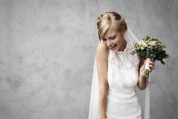 Joyous bride holding flowers in studio