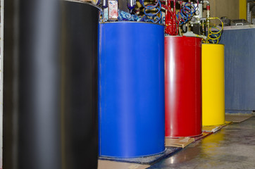 Large colorful barrels of ink in print production plant. Paint for printing roll of paper