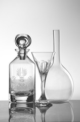 Still life of transparent wine or alcohol containers and crystal glass in white background