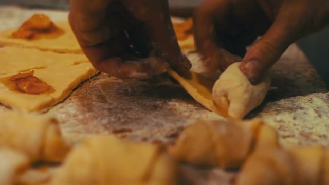 A woman puts on fresh pieces of dough apricot jam