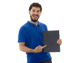 Young student holding and pointing at a black cover notebook. Space for text. Young man wearing blue polo shirt, white background, copy space.