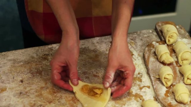 A woman puts on fresh pieces of dough apricot jam