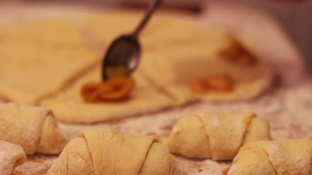 A woman puts on fresh pieces of dough apricot jam