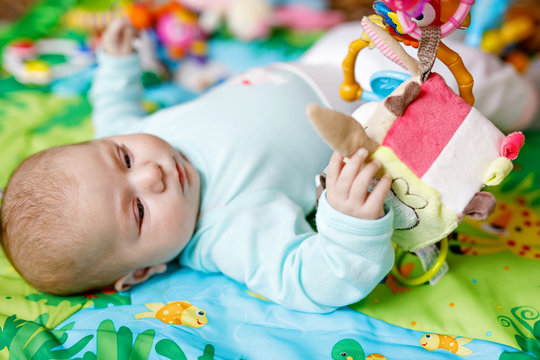 Cute adorable newborn baby playing on colorful toy gym