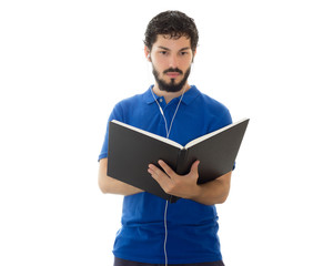 Young scholar checks notes in his notebook and hears music on the headset. Young man wearing blue polo shirt, white background, copy space.