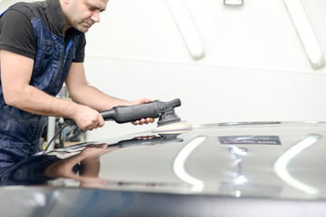 Man on a car wash polishing car with a polish machine