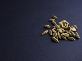 Cardamom pods in a pile, isolated on dark background