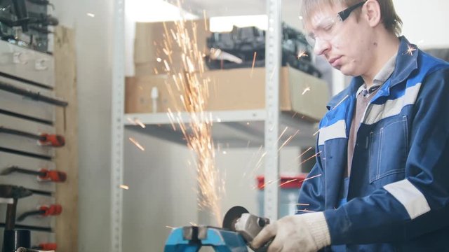Mechanic at work - circular saw sparkles when worker grinding metal detail hamstrung automobile repairin
