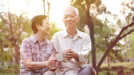 Healthy Asian senior couple drinking coffee in morning park together