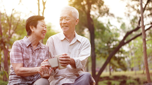 Healthy Asian senior couple drinking coffee in morning park together