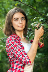 A young girl is sitting outdoors on the grass in a tree, brooding look, a summer day outdoors in the Park