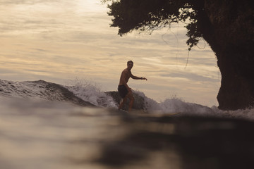 Indonesia, Java, man surfing at sunset