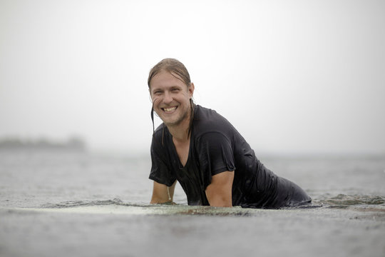 Indonesia, Java, smiling man on surfboard on the sea