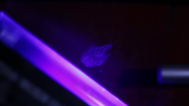 CSI Expert detecting fingerprints with UV lamp