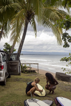 Indonesia, Java, two women preparing surfboard at the coast