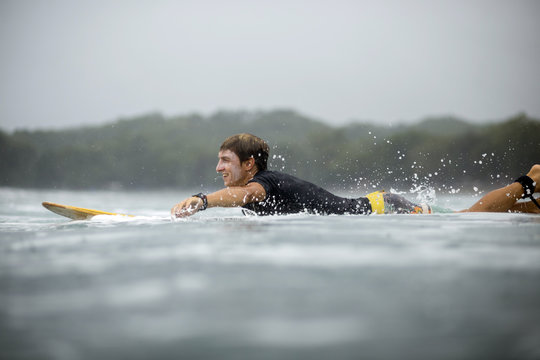 Indonesia, Java, man lying on surfboard on the sea