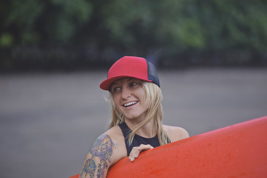 Smiling woman carrying surfboard on the beach