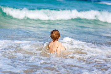 little blond kid boy having fun on ocean beach in Florida