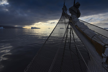 Details of a sailing ship in front of sunset in the arctic