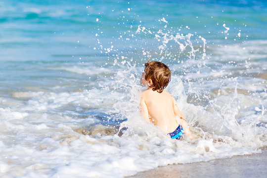 little blond kid boy having fun on ocean beach in Florida