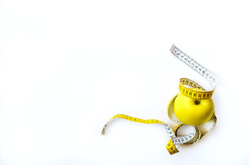 Measuring tape wrapped around fresh tasty yellow apple isolated on white background. Diet, weight...