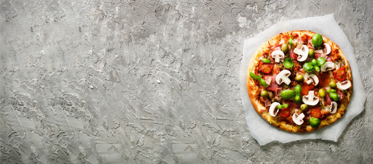 Fresh italian pizza with mushrooms, ham, tomatoes, cheese, olive, basil on grey concrete background. Copy space. Homemade with love. Fast delivery. Recipe and menu. Banner.