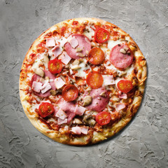 Fresh italian pizza with mushrooms, ham, tomatoes, cheese on on grey concrete background. Copy space. Homemade with love. Fast delivery. Recipe and menu. Top view. Square