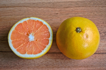 A whole and half grapefruit on a wooden table