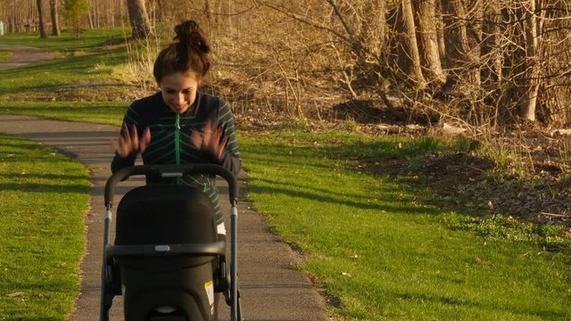 Young Athletic mom pushes stroller in  Spring