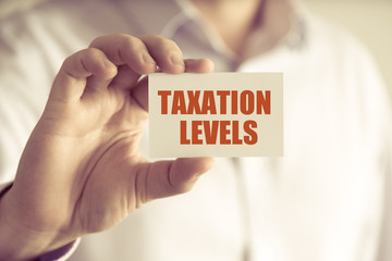 Businessman holding TAXATION LEVELS message card