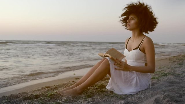 Inspired woman sitting seaside with book