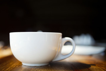   Coffee cup, on wooden table.