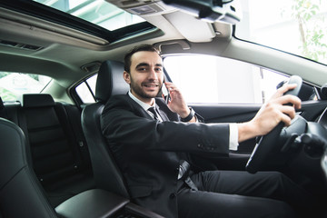 Man using his phone while driving the car. Business man driver speak phone white drive car