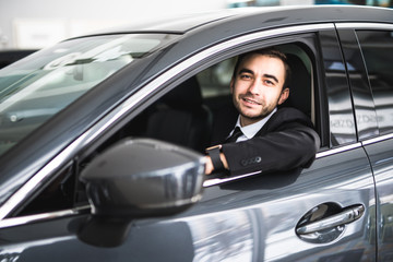 Fototapeta na wymiar happy smiling driver in the car, portrait of young successful business man