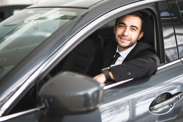 Fototapeta na wymiar happy smiling driver in the car, portrait of young successful business man