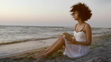 Relaxed young female sitting seaside with book