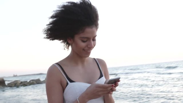 Smiling young woman reading text message on phone