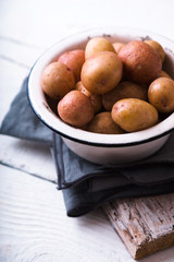 Raw potatoes in a white bowl on a napkin