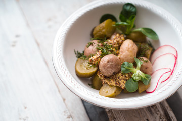 Salad with potato and radish in a white ceramic bowl
