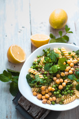 Salad with fusilli, chickpeas, grass in a white bowl copy space