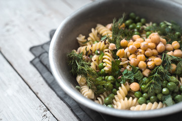 Salad with fusilli, chickpeas, grass in a metal bowl top view
