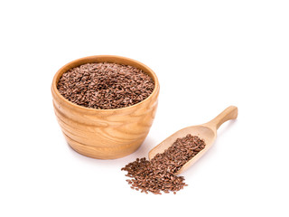 Wooden bowl with linseeds or flax seeds and a spoon to the right of it on white background
