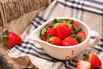 Bowl with fresh strawberry on blue wooden table.