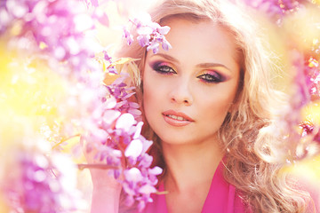 Naklejka premium Beautiful girl in lilac dress in flower garden