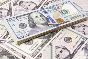 A stack of one hundred dollar bills on a background of dollars 