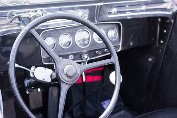Obraz premium Steering wheel and dashboard in historic vintage car. Retro automobile interior scene. Old vehicle.