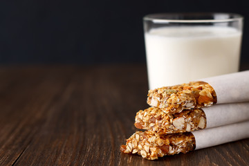 Homemade no bake granola bars with glass of milk on rustic wooden table.