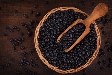 Black beans in scoop on wooden background